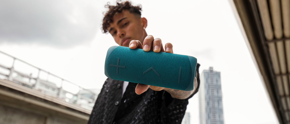 Teal BlueAnt X2i Bluetooth speaker held in one hand