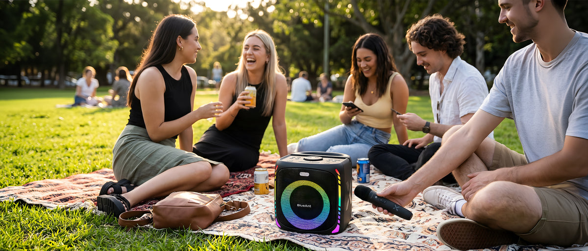 Portable BlueAnt X4i Bluetooth party speaker outdoors on grass, lights on